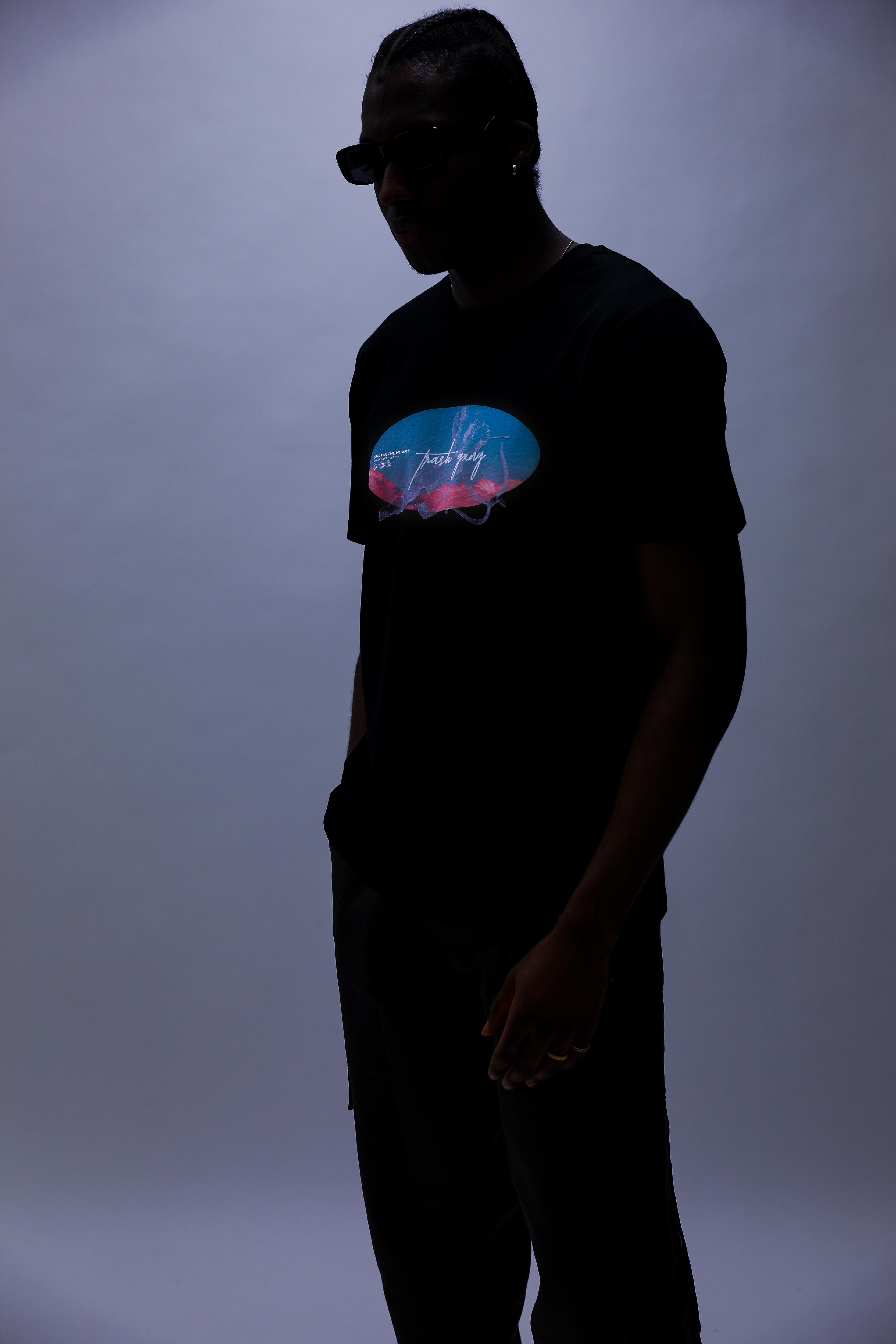 Front design in dark mood lighting on a model wearing 'In the Heart' Black Heavy Cotton Oversized Tee